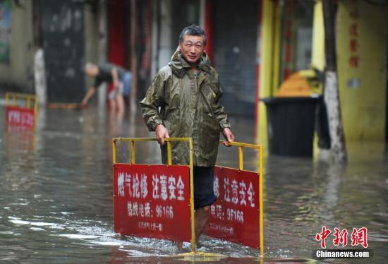 南昌市政工作人员在积水中摆放指示牌，提醒过往车辆和行人。刘占昆 摄