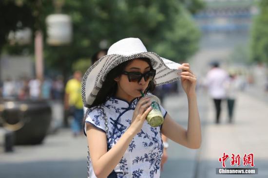 5月25日，北京高温，行人在北京前门大街行走。当日，北京发布今夏首个高温预警，午后户外温度高达35度。 发 熊然 摄