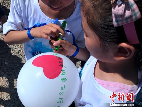 图为随迁农民工子女在心愿气球上写下自己参与暑期特训营对自己的期望。　张欢 摄